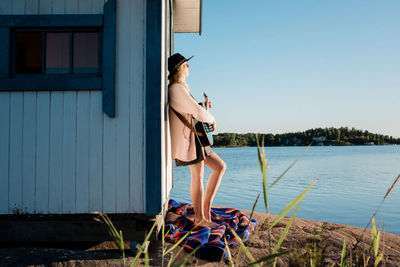 Woman leaning on a beach hut playing the guitar in the sun