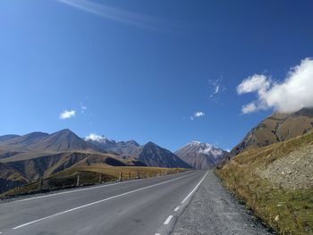 Road by mountains against blue sky