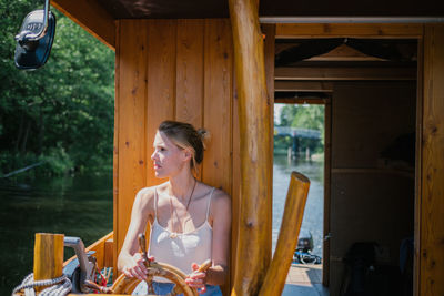 Woman sitting by wheel in boat on lake