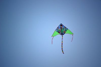 Low angle view of kite flying against clear blue sky