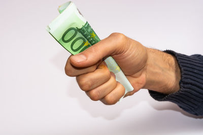 Close-up of hand holding paper over white background