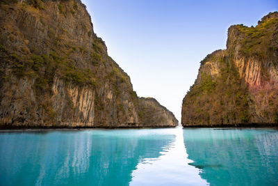 Rock formations by sea against clear blue sky