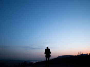 Silhouette of person standing on mountain against sky