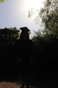 Silhouette woman standing by tree against sky