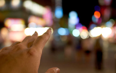 Close-up of hand holding illuminated street at night