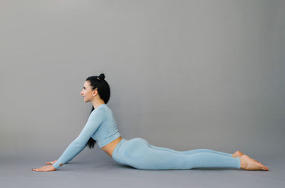Young attractive woman practicing yoga concept, stretching in cobra exercise, bhujangasana pose