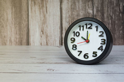 Black alarm clock isolated on wooden desk. the clock set at 10 o'clock. deadline concept.