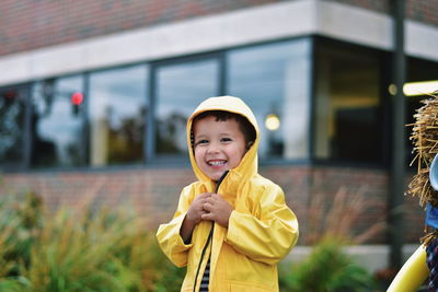 Portrait of cute smiling boy wearing yellow jacket outdoors