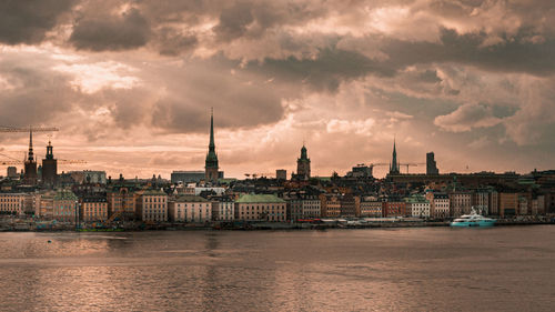 View of buildings at waterfront against cloudy sky