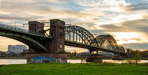 Arch bridge over river against cloudy sky