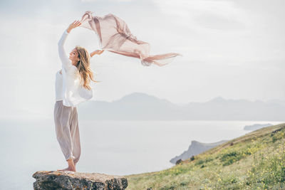 Full length of woman with arms outstretched standing on mountain