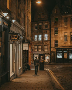 Rear view of people walking on street amidst buildings at night