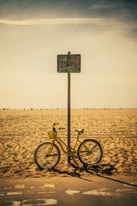 Bicycle sign on beach against sky