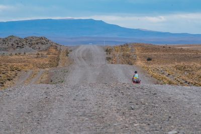 Rear view of person on arid landscape against sky