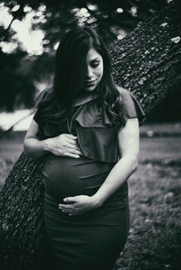 Beautiful woman standing by tree against plants