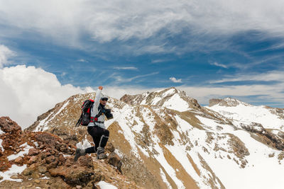 Rear view of man walking on mountain against sky
