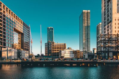 City at waterfront against blue sky