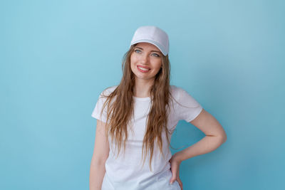 Attractive friendly young woman smiling happily wearing a white t-shirt and cap