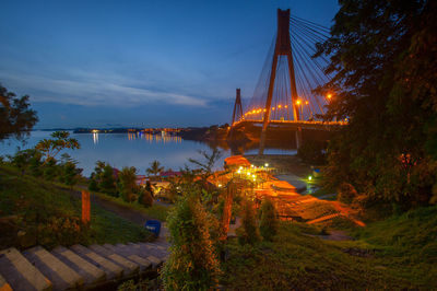 Illuminated bridge over river against sky at night