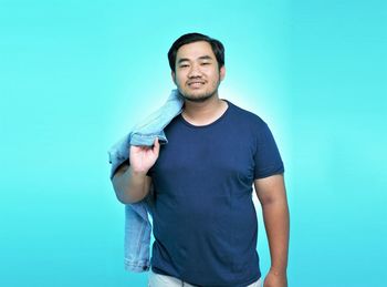Portrait of young man standing against blue background