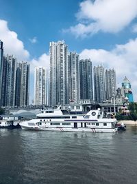 Boats in city by buildings against sky