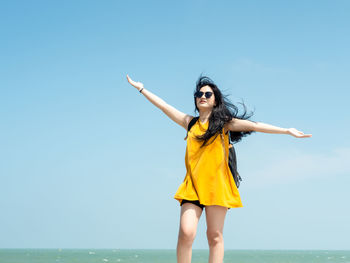 Young woman standing in front of sea against sky