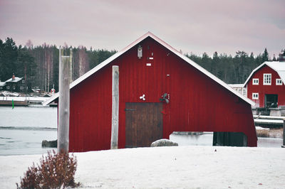 Snow covered houses by trees against sky