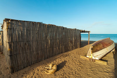 View of bamboo hut next to sea against clear sky