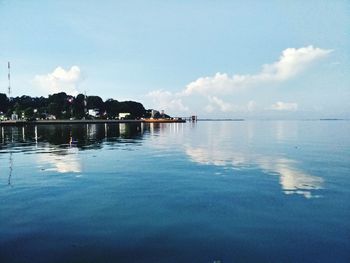 Swimming pool by lake against sky