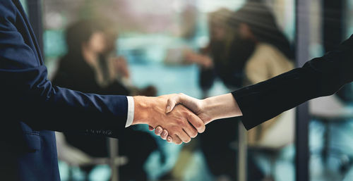 Midsection of business colleagues shaking hands