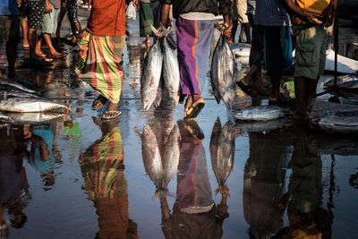 Low section of people standing on puddle in city