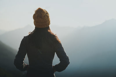 Rear view of man looking at mountains against sky