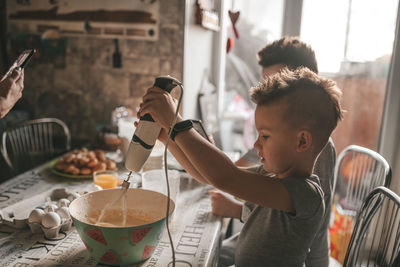 Side view of boy mixing batter in bowl