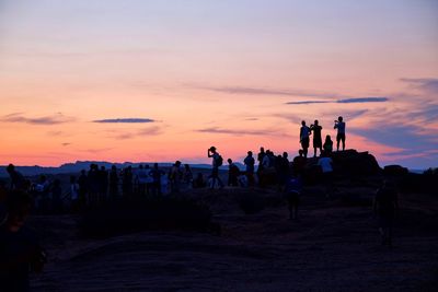 Silhouette people on desert against sky during sunset