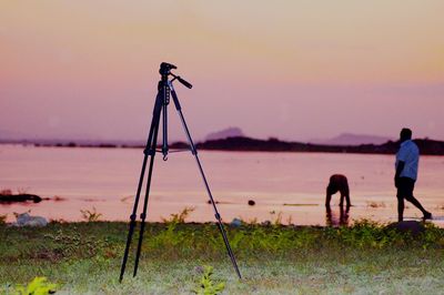 People working on field against sky during sunset