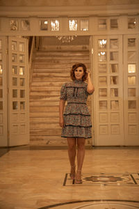 Full length portrait of woman standing against building