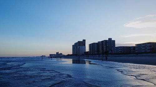 Sea by city against sky