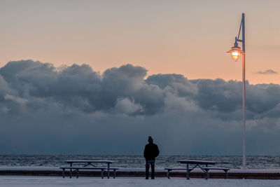 Man on beach against sky during sunset