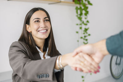 Happy recruiter shaking hand with candidate in office