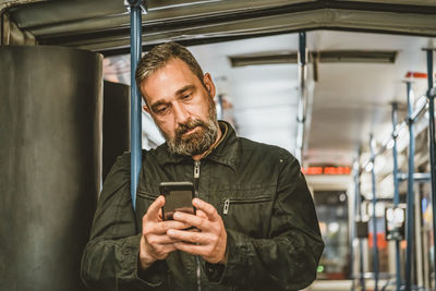 Man reading from mobile phone screen while traveling on metro.wireless internet on public transport 