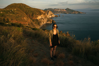 Full length portrait of young woman standing on mountain