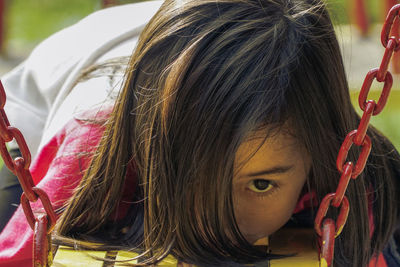 Close-up of girl laying down on swing at park