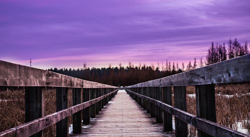 Footpath by bridge against sky during sunset