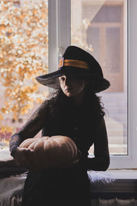 Halloween lady wearing witch cup. a woman in witch hat and halloween pumpkin near the windows