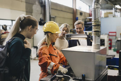 Female worker explaining businessman and his family in factory