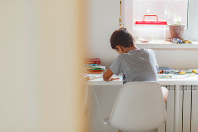 Rear view of boy painting at home