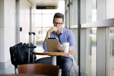 Businessman working on tablet computer while sitting in cafeteria at subway station