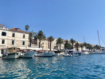 Sailboats moored in sea against clear blue sky