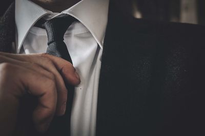 Midsection of man adjusting necktie