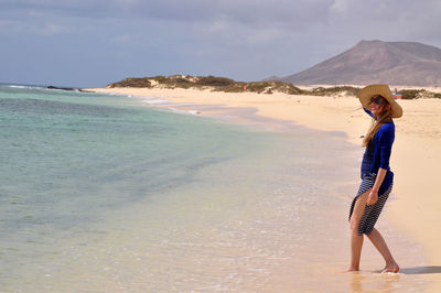 Woman standing on beach against sky